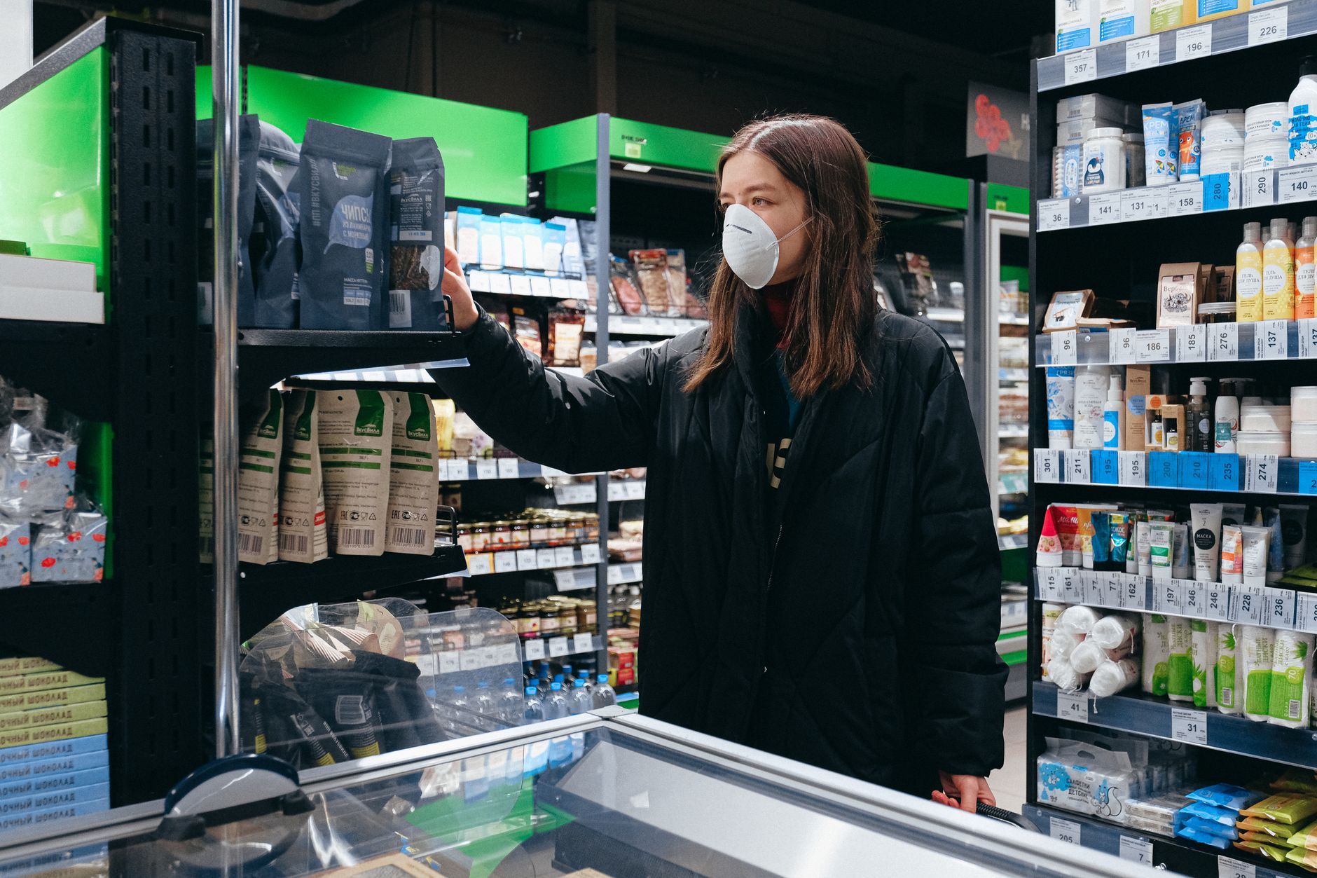 A woman wearing a face mask shops for groceries indoors, reflecting pandemic precautions.