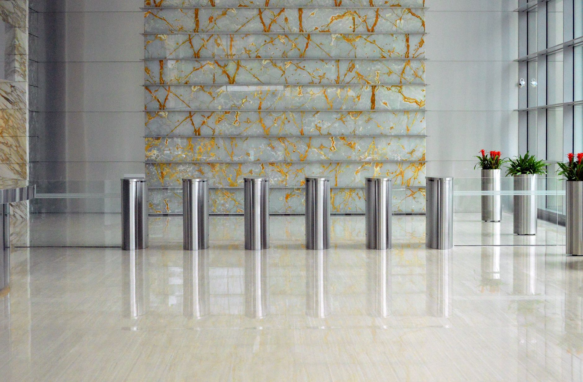 A sleek corporate lobby featuring marble walls, metal dividers, and glass windows for a sophisticated design.
