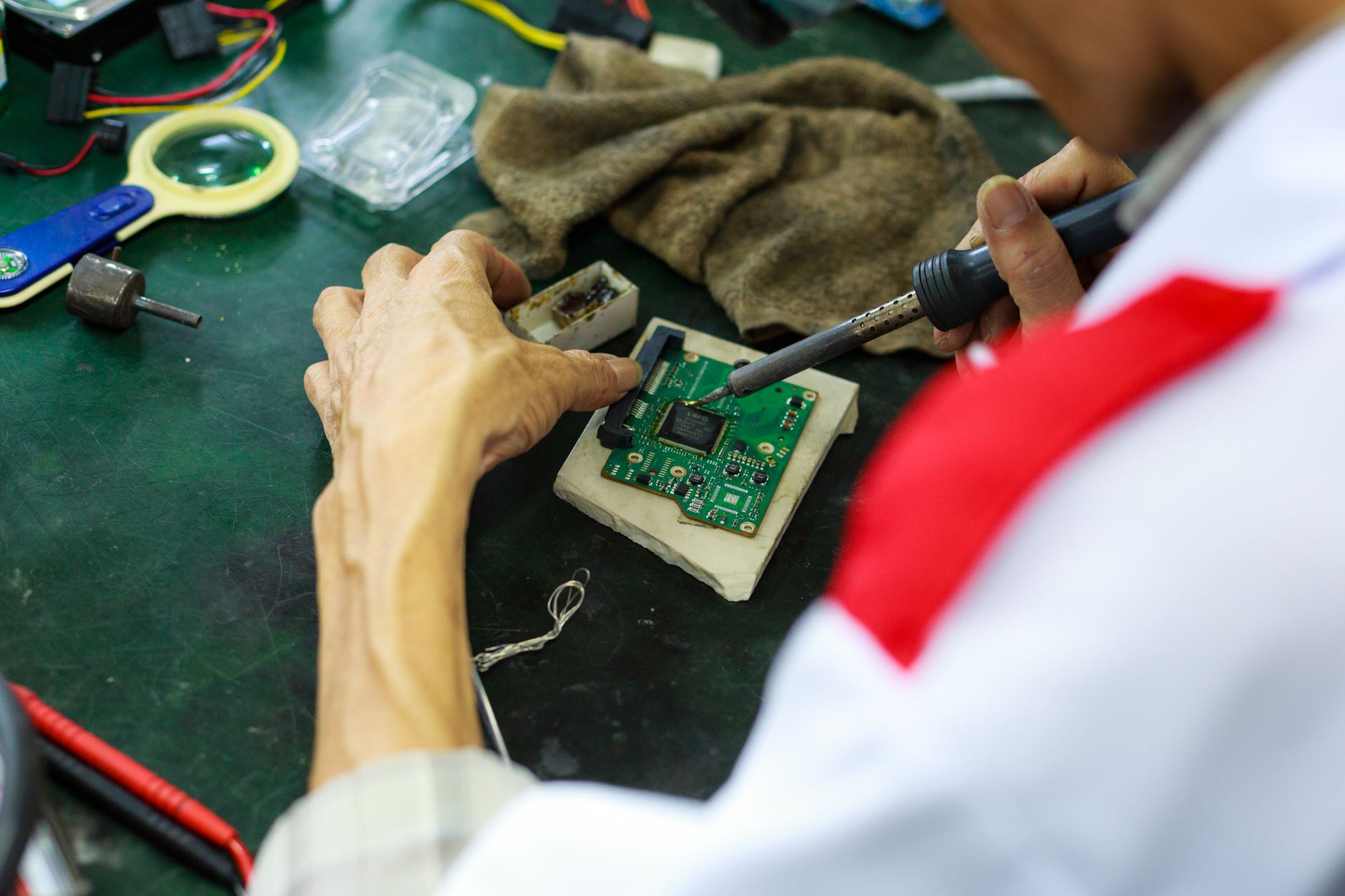 A skilled technician uses a soldering iron to repair and solder a circuit board.