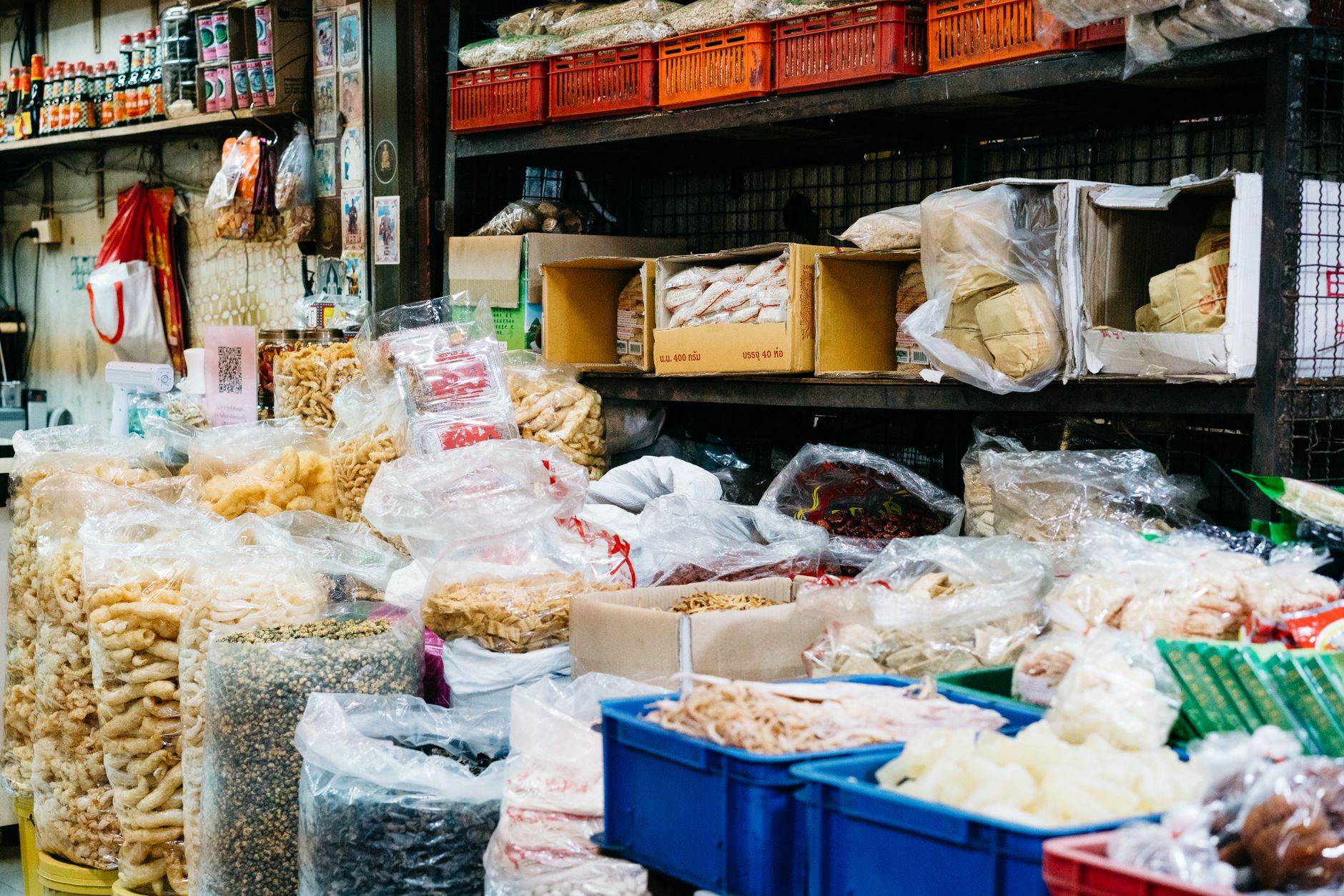 Colorful street market stall displaying a variety of dry foods in bags and boxes.