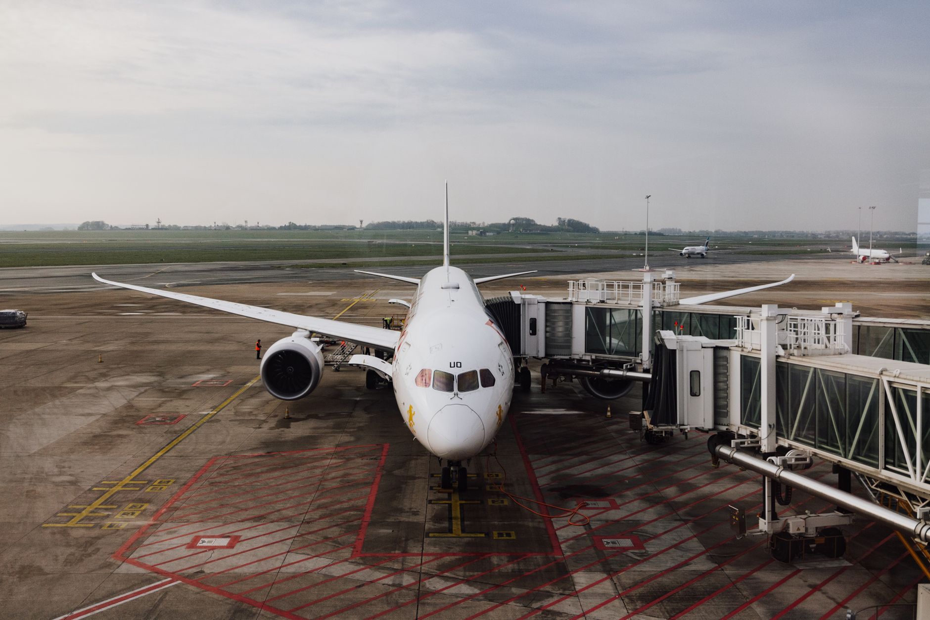 A modern jet airplane docked at an airport terminal gate, ready for boarding on a cloudy day.