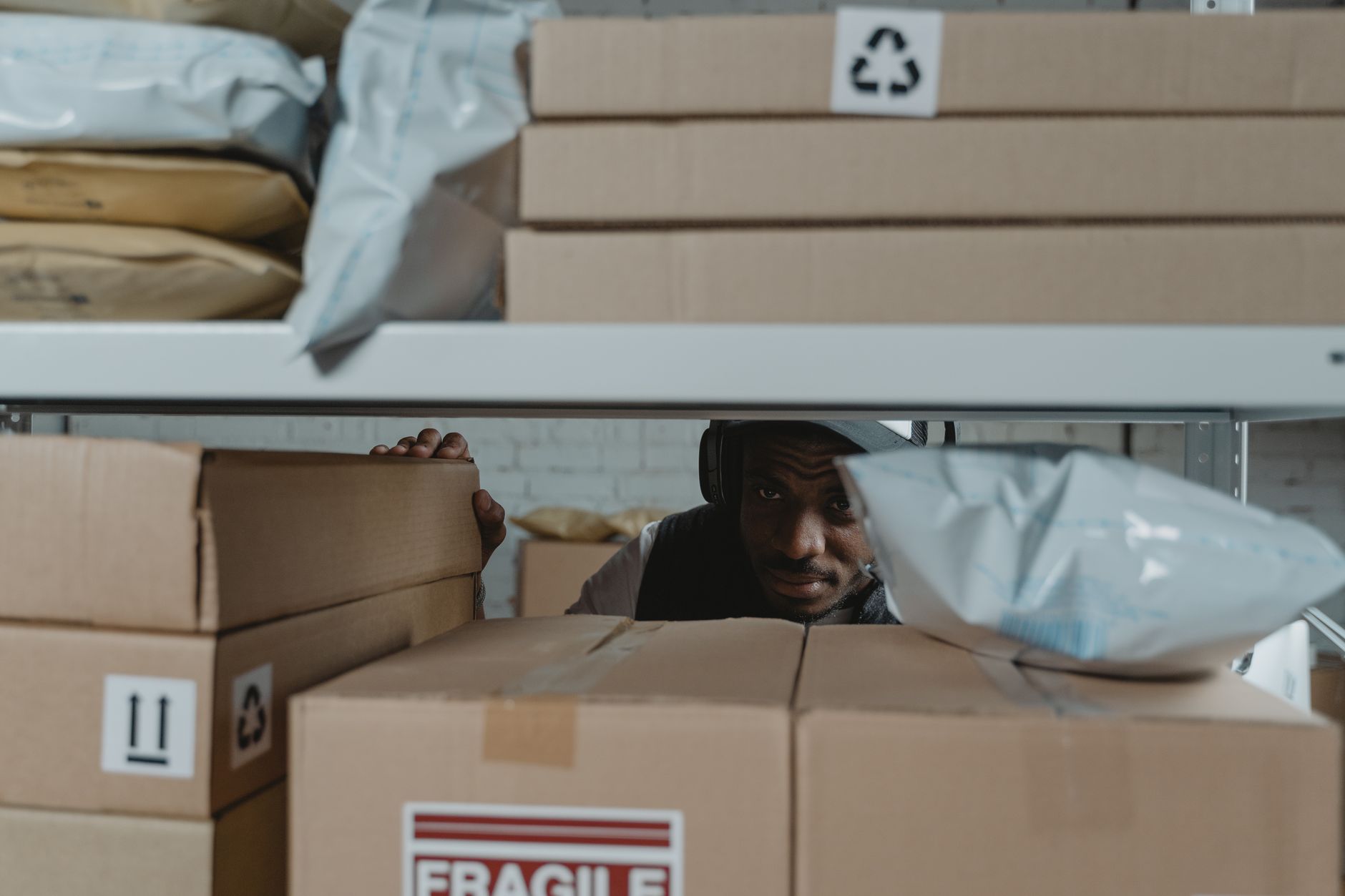 Warehouse worker inspecting shipment packages on shelves, ensuring quality and accuracy in logistics.
