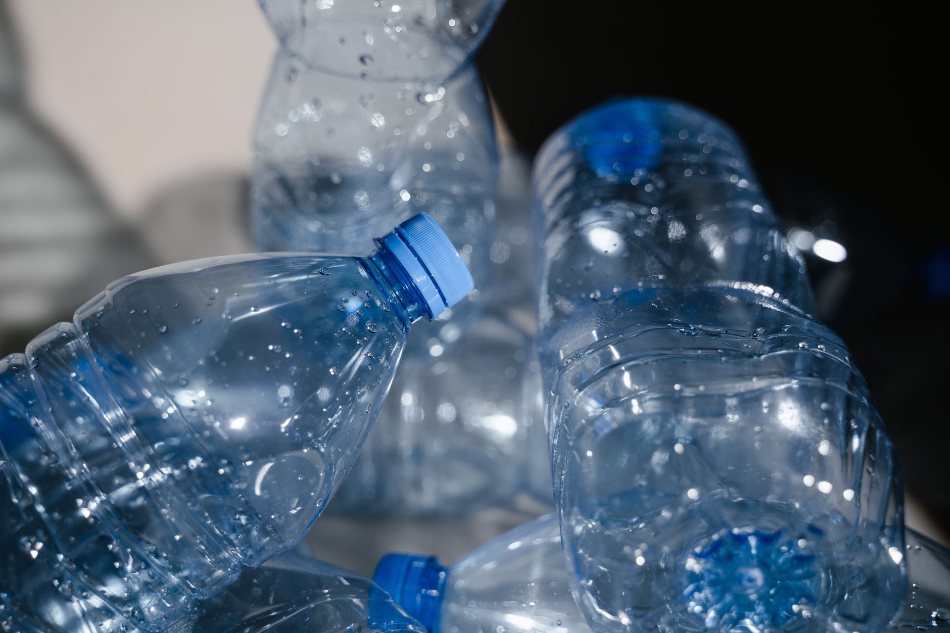 Multiple empty plastic bottles with water droplets in a close-up shot, highlighting recycling.